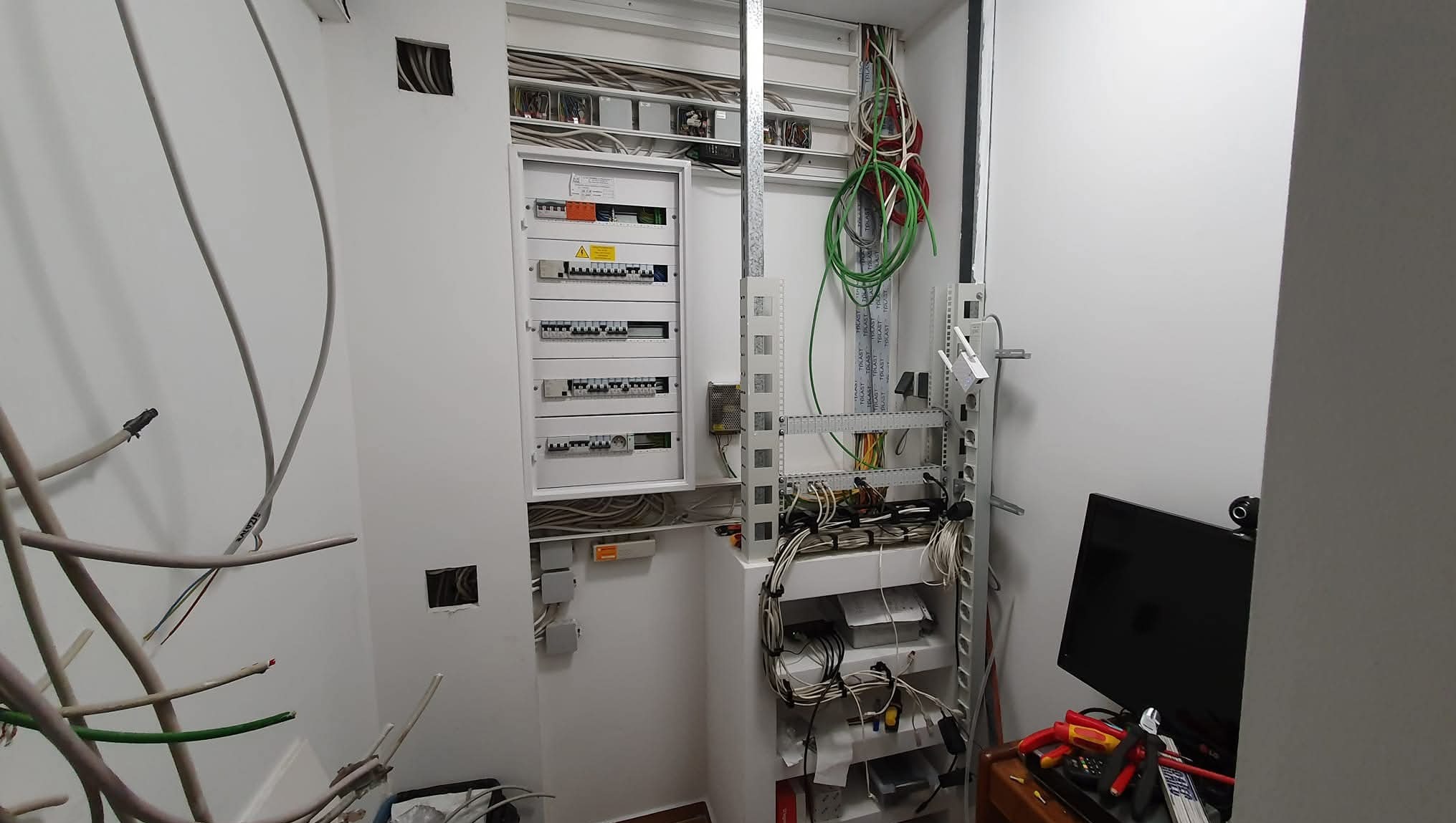 Rozdzielnia elektryczna po montażu w białym pomieszczeniu. Widoczne kable, zabezpieczenia i elementy instalacji. Praca wykonana schludnie i profesjonalnie. 'Po'.