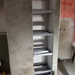 MydMar - Szkielet regału z płyty GK z metalowymi profilami na półki, widoczne narzędzia i poziomica. Ściana w tle przygotowana pod płytki.