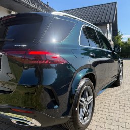 KZ Garage Krystian Zbozień - Błyszczący, ciemnozielony Mercedes GLE po detailingu, widoczny z tyłu na kostce brukowej w słoneczny dzień. Chromowane elementy i czyste opony.