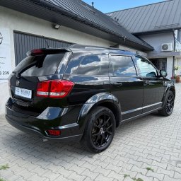 KZ Garage Krystian Zbozień - Czarny Fiat Freemont po detailingu, zaparkowany na kostce brukowej przed budynkiem. Widoczne odbicie chmur w lakierze i przyciemnione szyby.