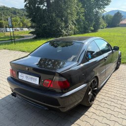 KZ Garage Krystian Zbozień - Czarne BMW E46 Coupe z przyciemnionymi szybami, zaparkowane na kostce brukowej. Widoczny emblemat 'KZ Garage Detailing' na tablicy rejestracyjnej.