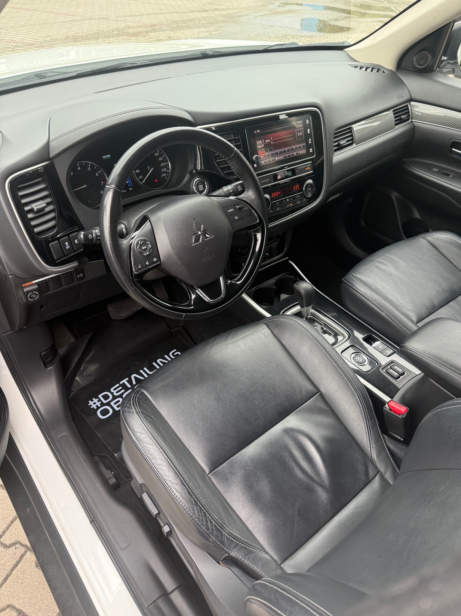 Wnętrze samochodu po praniu tapicerki w Jazowsku. Skórzane fotele, czysta deska rozdzielcza i dywaniki detailingowe. Widok z perspektywy pasażera.