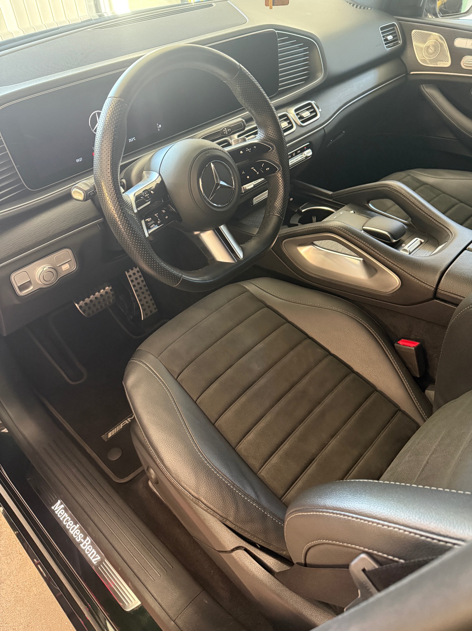 Wnętrze luksusowego, czarnego Mercedesa GLE z ciemną tapicerką, widok na kierownicę, deskę rozdzielczą i fotel kierowcy. Widoczne detale wykończenia AMG.