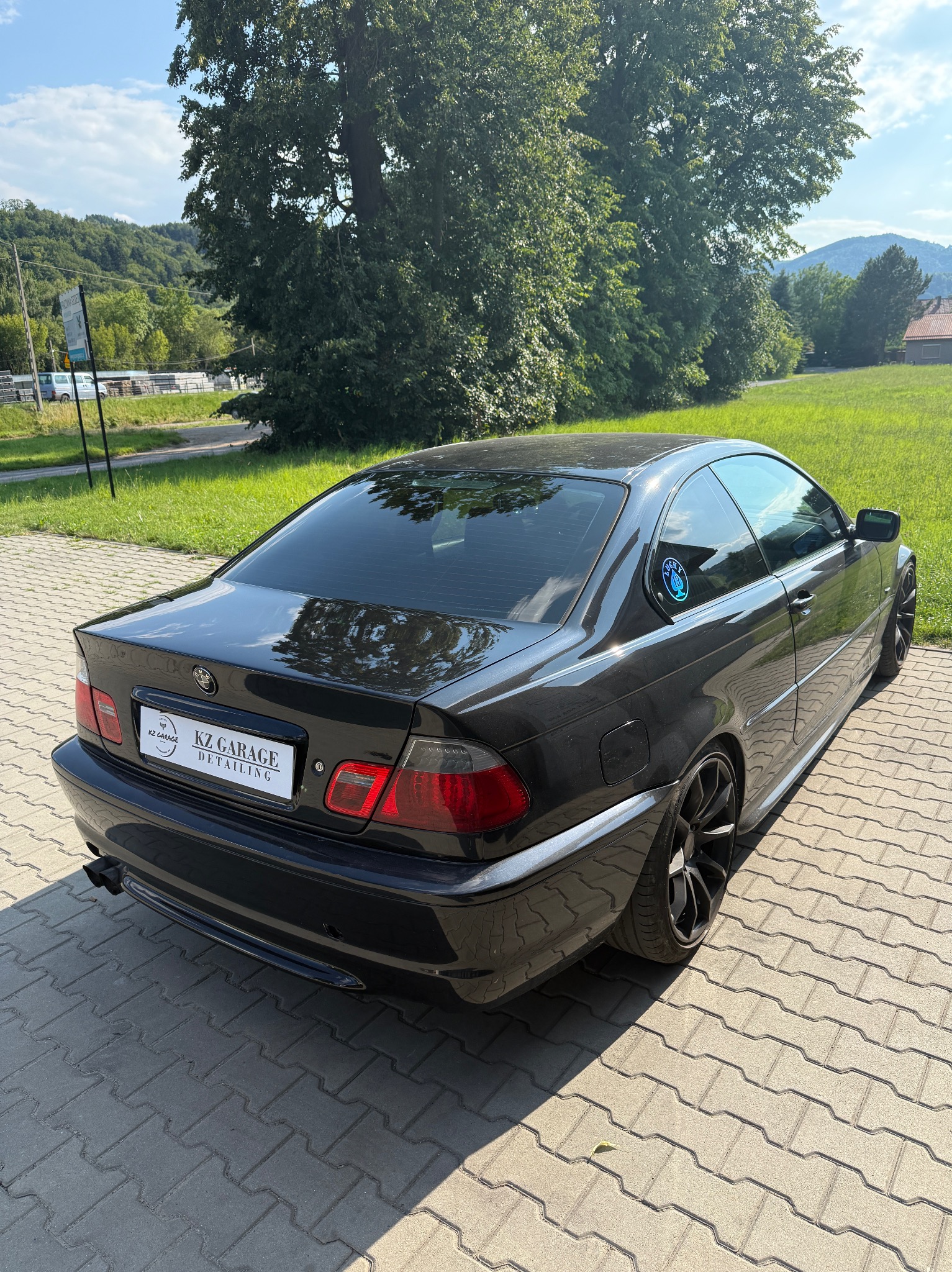 Czarne BMW E46 Coupe z przyciemnionymi szybami, zaparkowane na kostce brukowej. Widoczny emblemat 'KZ Garage Detailing' na tablicy rejestracyjnej.