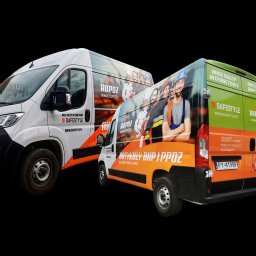 Agencja Reklamowa ActionPrint - Dwa samochody dostawcze z oklejeniem reklamowym firm Safestyle i Ropoz, prezentujące artykuły BHP i PPOŻ. Jeden biały, drugi w kolorach pomarańczowym i zielonym.