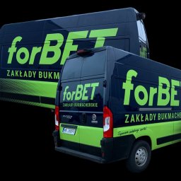 Agencja Reklamowa ActionPrint - Dwa samochody dostawcze z brandingiem 'forBET' w Ostródzie. Kontrastowe, zielono-czarne barwy, logo i hasło 'Zakłady Bukmacherskie'.