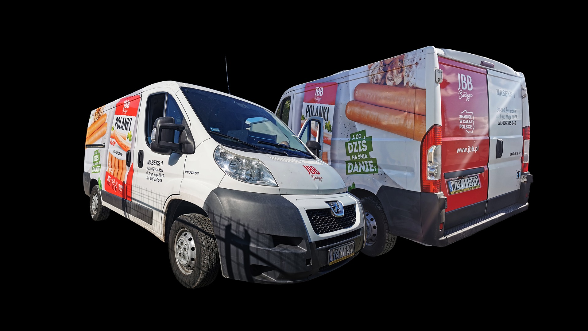 Dwa busy z brandingiem JBB Bałdyga, prezentujące grafiki kiełbasek Polanki i hasła reklamowe. Czerwono-biała kolorystyka, widoczne numery rejestracyjne. Promocja marki na pojazdach.