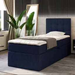 Niebieskie łóżko tapicerowane z zagłówkiem w sypialni z lustrem i roślinami, oświetlone lampą nocną. Całość w nowoczesnym stylu z elementami dekoracyjnymi.