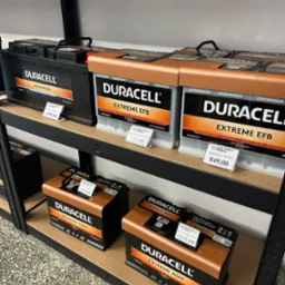 Półki sklepowe z akumulatorami Duracell Advanced, Extreme EFB i Extreme AGM z cenami. Widoczne różne modele i parametry.