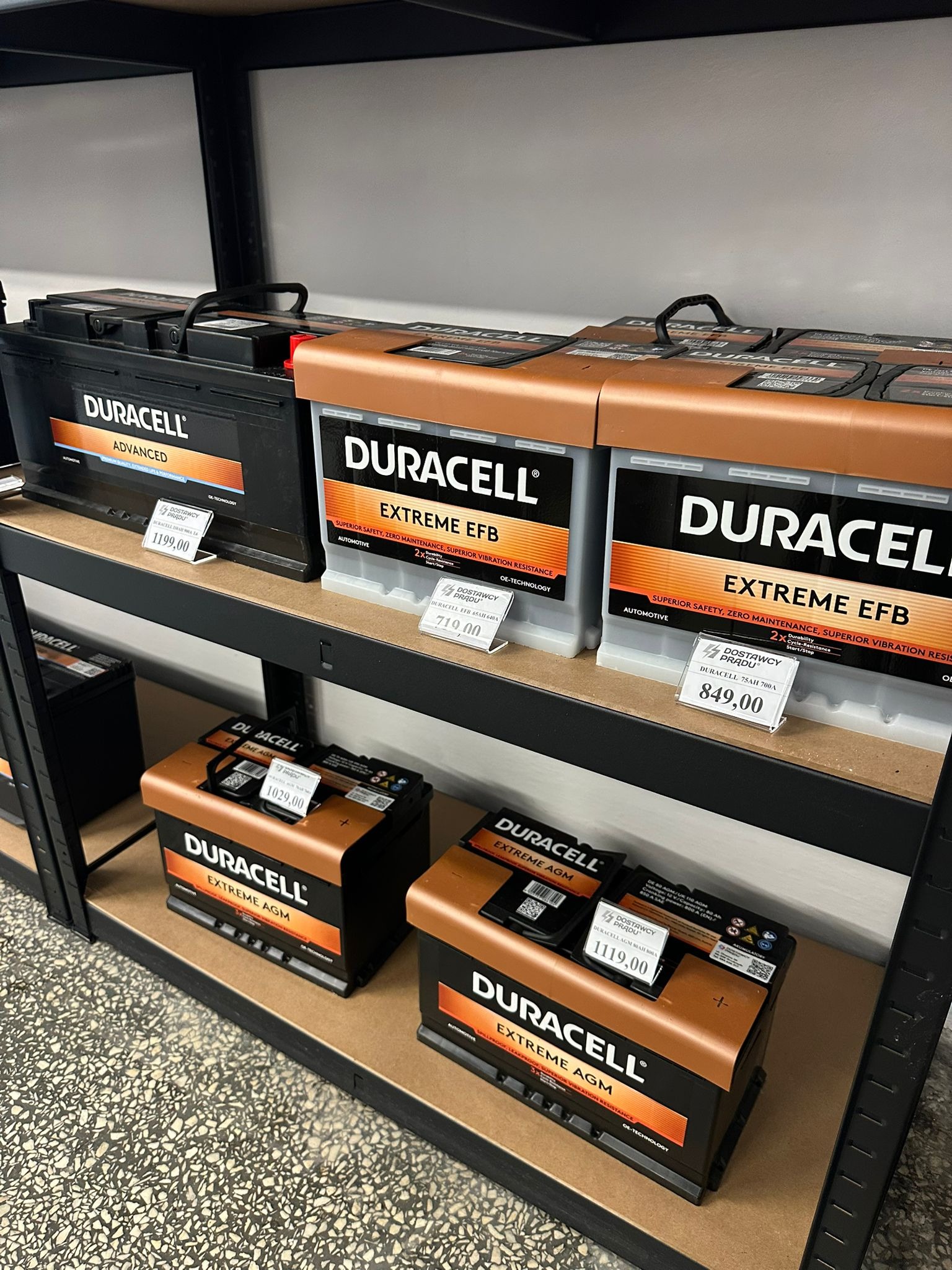 Półki sklepowe z akumulatorami Duracell Advanced, Extreme EFB i Extreme AGM z cenami. Widoczne różne modele i parametry.