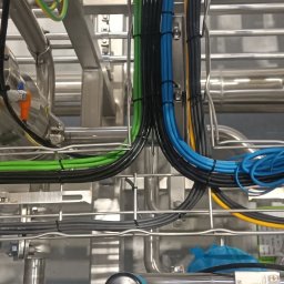 I-Markon - Profesjonalnie ułożone, kolorowe kable elektryczne w metalowej konstrukcji, zabezpieczone opaskami zaciskowymi. Widoczne rury i elementy instalacji.