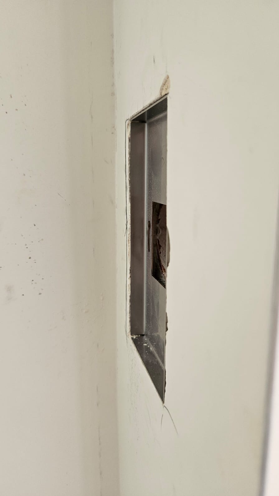 Metalowa puszka instalacyjna w ścianie, widoczne przewody. Przygotowanie do montażu gniazdka elektrycznego w nowym budynku. Widok z boku, surowy stan wykończenia.