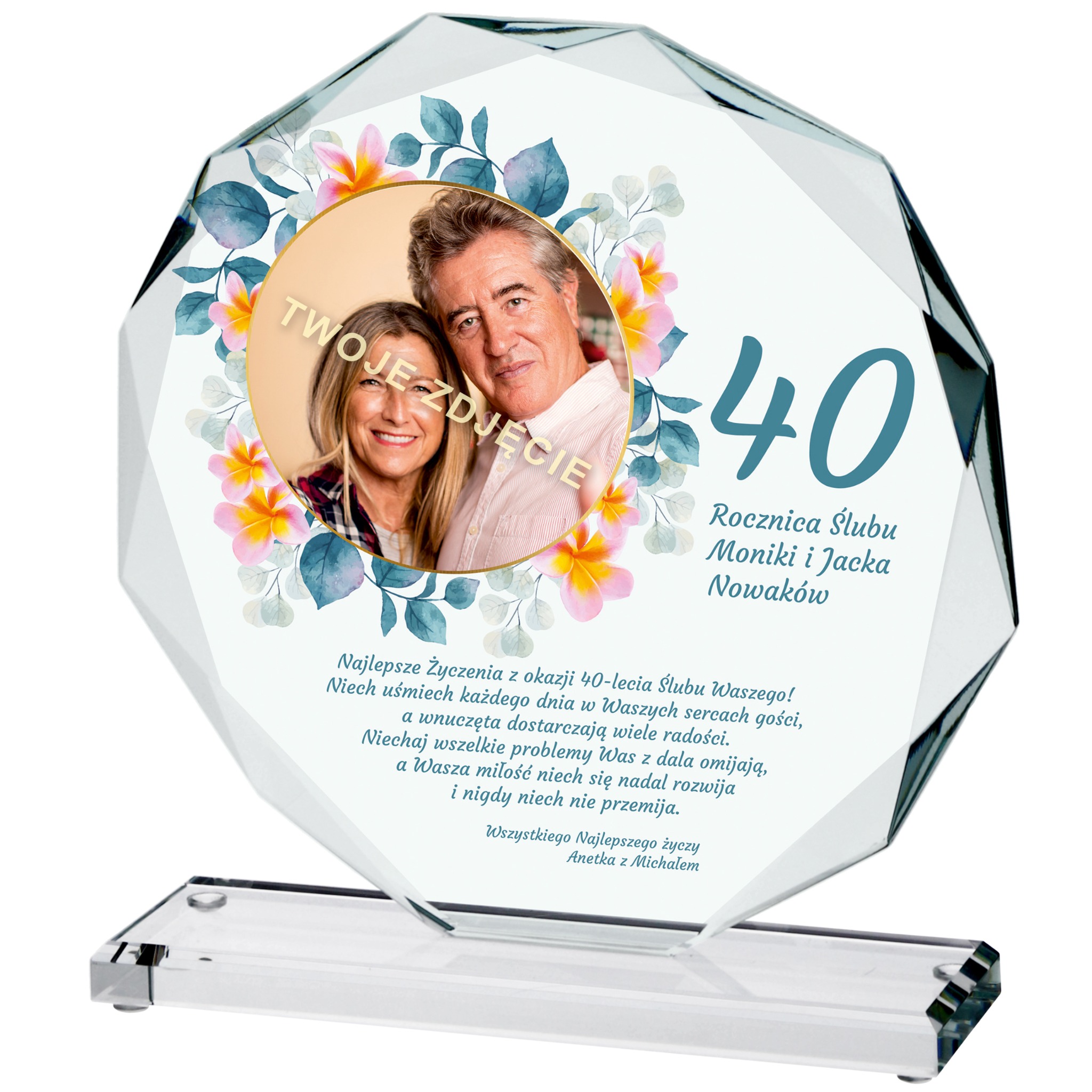 Szklana statuetka z nadrukiem zdjęcia pary i dedykacji z okazji 40 rocznicy ślubu, otoczona kwiatowym motywem, stojąca na przezroczystej podstawie.