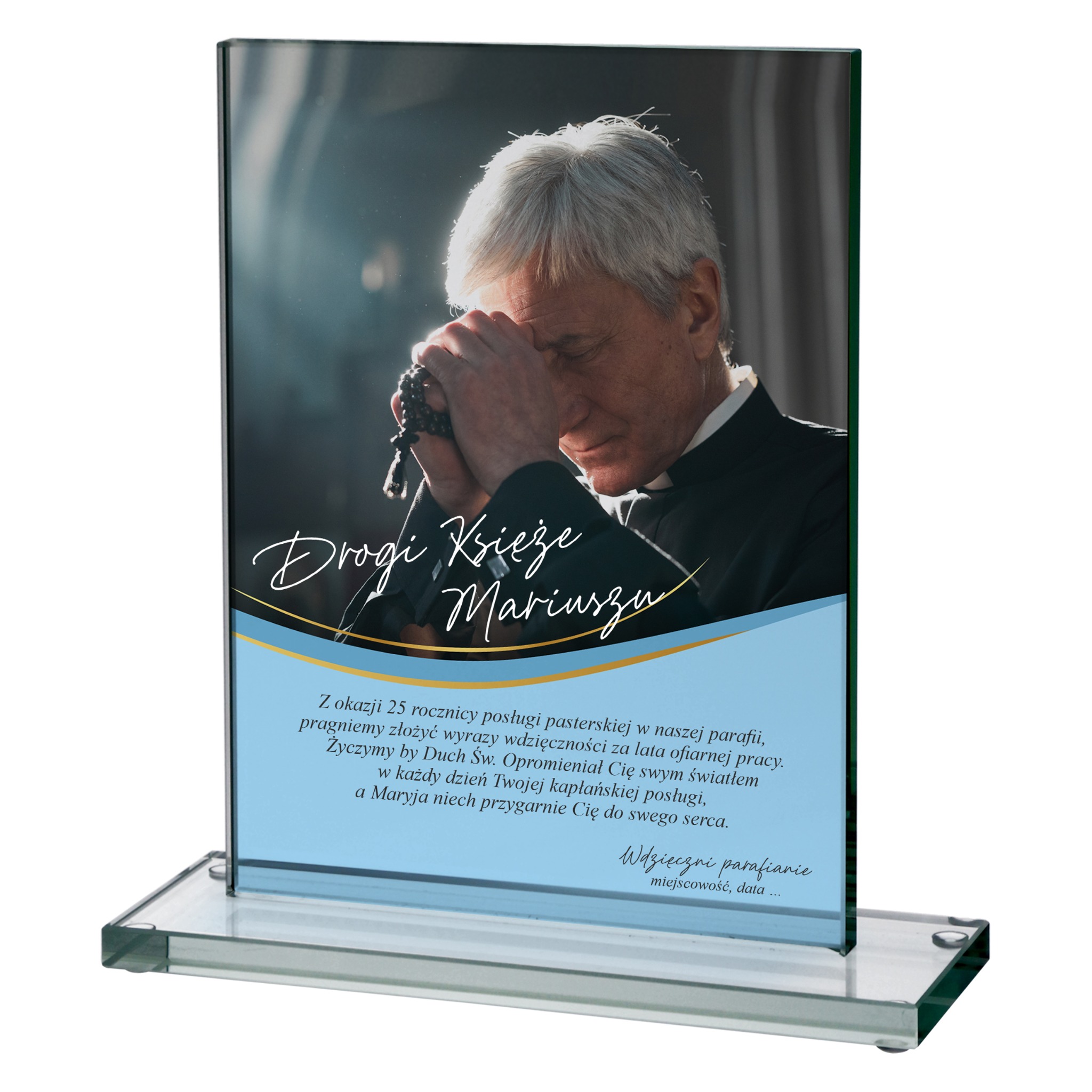 Szklana statuetka z nadrukiem portretu księdza i dedykacją na 25-lecie posługi, umieszczona na przezroczystej podstawie. Pamiątka od parafian.