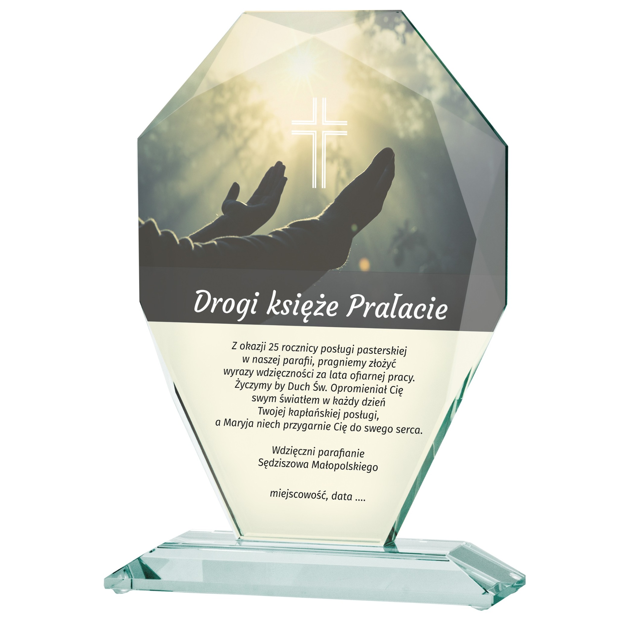 Szklana statuetka z dedykacją 'Drogi księże Prałacie' i motywem religijnym, elegancki upominek z okazji 25-lecia posługi duszpasterskiej. Transparentne szkło.