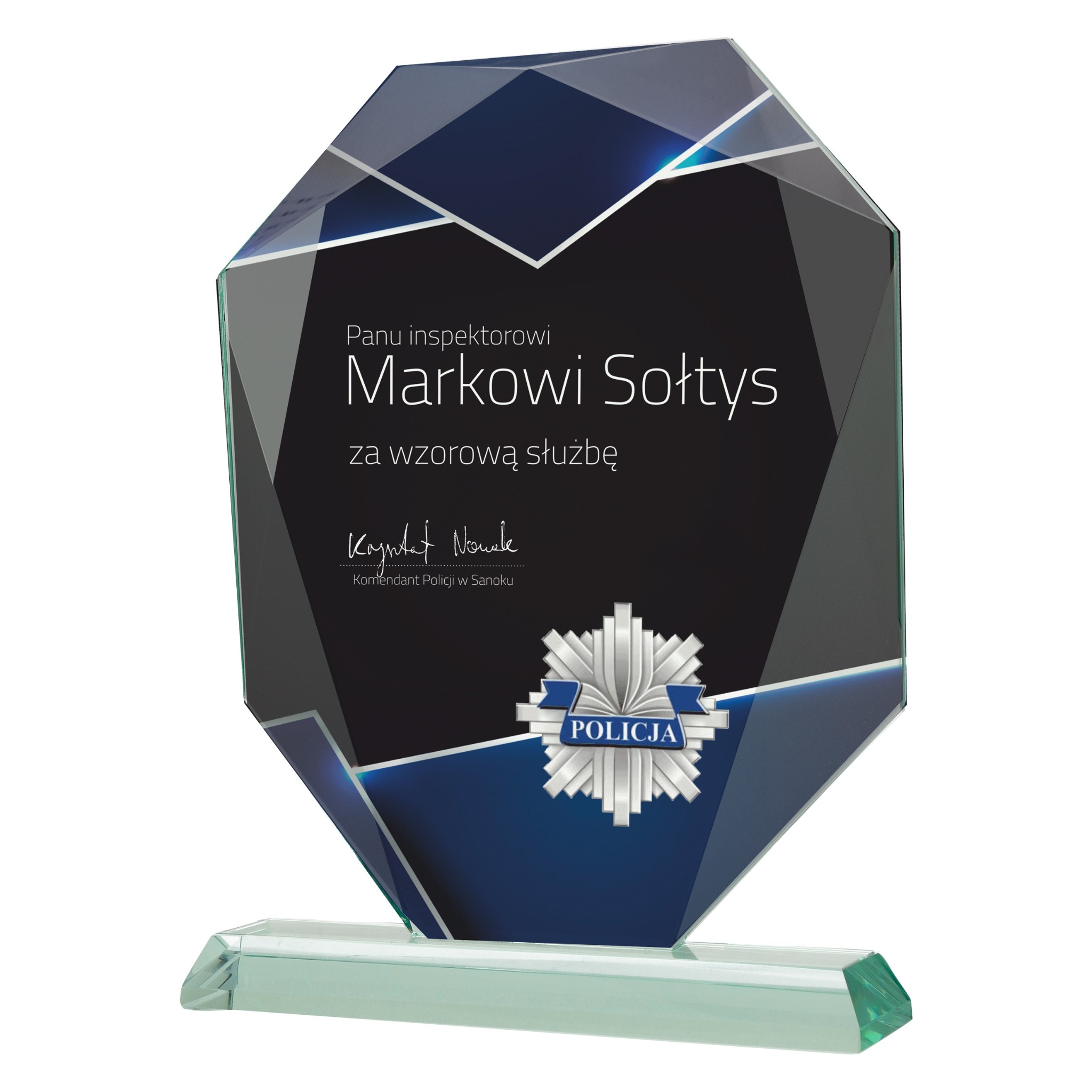 Szklana statuetka z grawerem dedykacji i logiem policji, wręczana jako podziękowanie za służbę, na białym tle. Elegancki prezent firmowy.