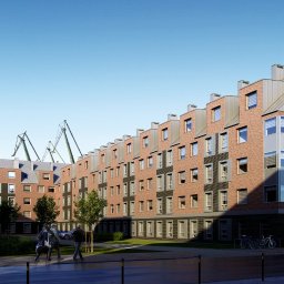 M-BACH MICHAŁ BACHANOWICZ - Wizualizacja budynku mieszkalnego z cegły z szarymi dachami i oknami, na tle błękitnego nieba i dźwigów portowych. Widoczni przechodnie i rowery.