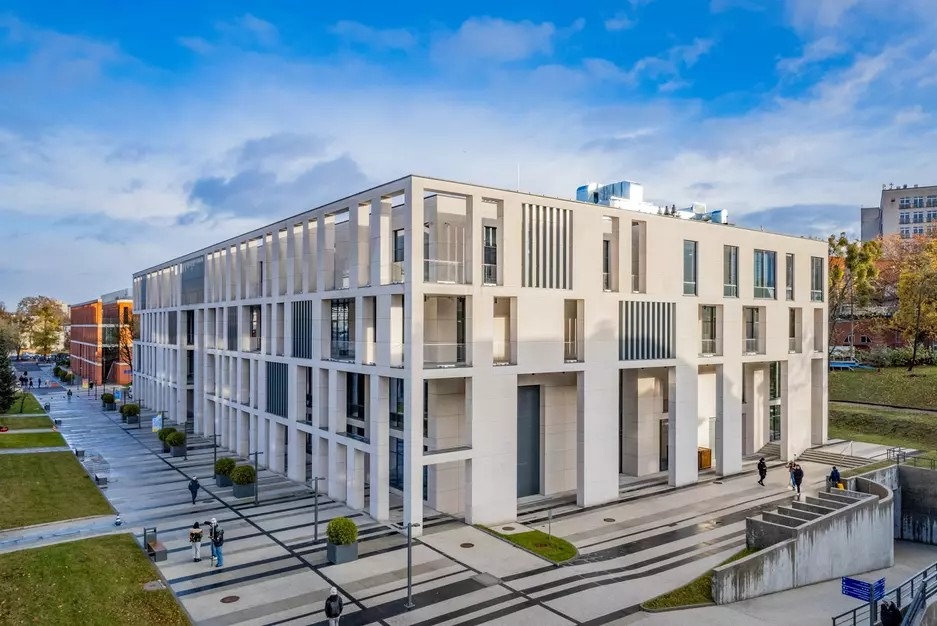 Nowoczesny budynek Centrum Ekoinnowacji Politechniki Gdańskiej z charakterystyczną fasadą w jasnych barwach, widziany z perspektywy zewnętrznej w słoneczny dzień.