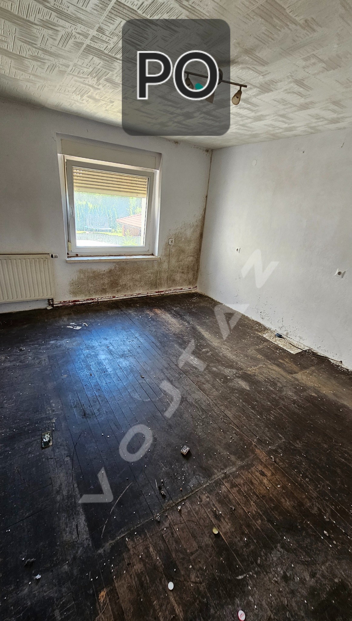 Pokój po sprzątaniu: ciemna podłoga, białe ściany z plamami, okno z żaluzjami. Widoczny efekt 'po' z nakładką tekstową.