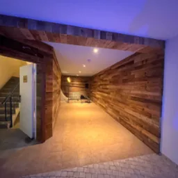 Drewniana boazeria na ścianach i suficie, widok na schody w Świnoujściu. Naturalne drewno, rustykalny styl, ciepłe oświetlenie, jasne płytki podłogowe.