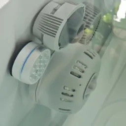 Biały, okrągły element z otworami i diodami LED, prawdopodobnie dysza do hydromasażu, zamontowany na białej powierzchni w jacuzzi.