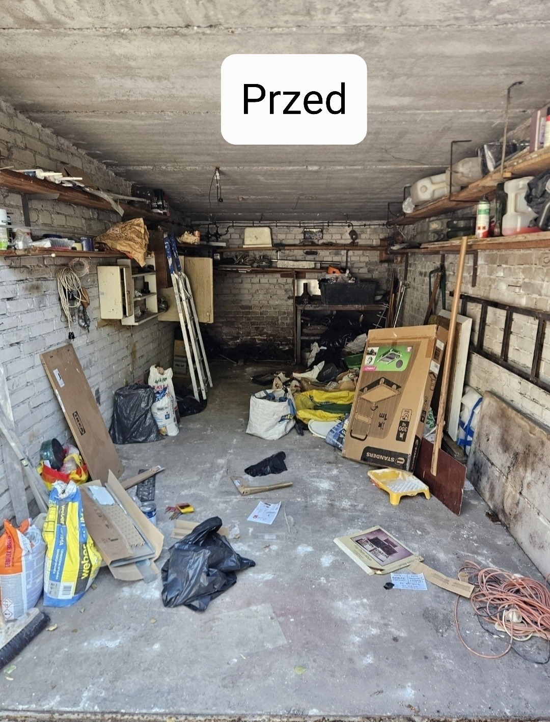 Zagracony garaż w Kaliszu przed sprzątaniem. Widoczne worki ze śmieciami, kartony i inne przedmioty. Na górze zdjęcia napis 'Przed'.