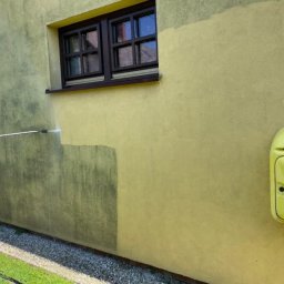 VADYM FEDORCHUK FIRMA USŁUGOWA - Żółta elewacja domu czyszczona myjką ciśnieniową, widoczna różnica między umytą a brudną powierzchnią pod oknem. Z prawej skrzynka gazowa.