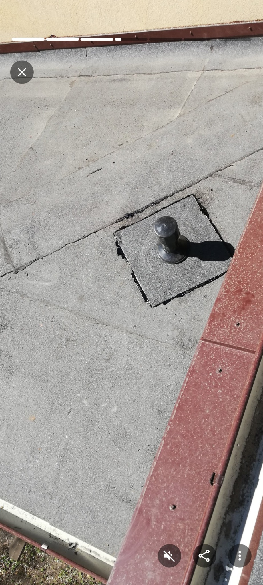 Szczegółowe ujęcie dachu pokrytego papą z metalowym odpowietrznikiem w Gdyni. Widoczne pęknięcia i nierówności na powierzchni dachu oraz fragment obróbki blacharskiej.