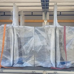 Mat Logis - Zabezpieczone folią i pasami meble wewnątrz przestrzeni ładunkowej busa transportowego, gotowe do przewozu. Widoczne drewniane listwy mocujące.