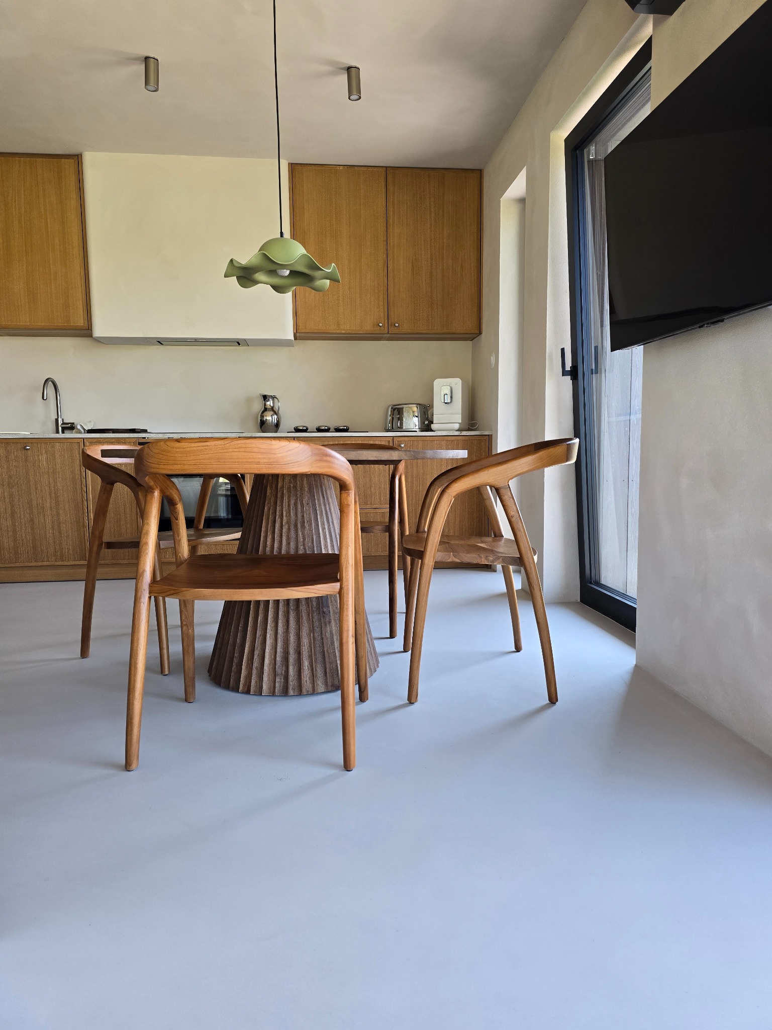 Jasnoszara posadzka w kuchni z drewnianymi meblami i stołem. Minimalistyczny design, nowoczesne wykończenie. Widok na okno i telewizor.