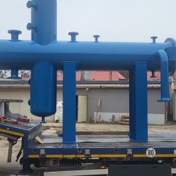 ANL Serwis Tomasz Nawrocki - Niebieska, pomalowana konstrukcja stalowa na naczepie ciężarówki. Widoczna drabina, budynki w tle i pochmurne niebo. Elementy konstrukcji spawane.