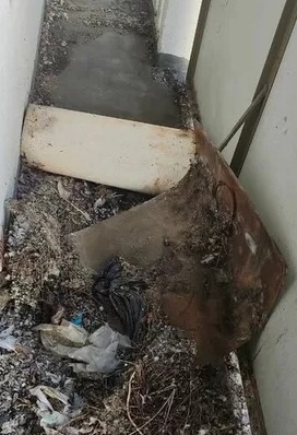 Zdemontowana wanna i gruz w wąskiej łazience w trakcie prac remontowych. Widoczne ślady po starej instalacji i pozostałości po demontażu.