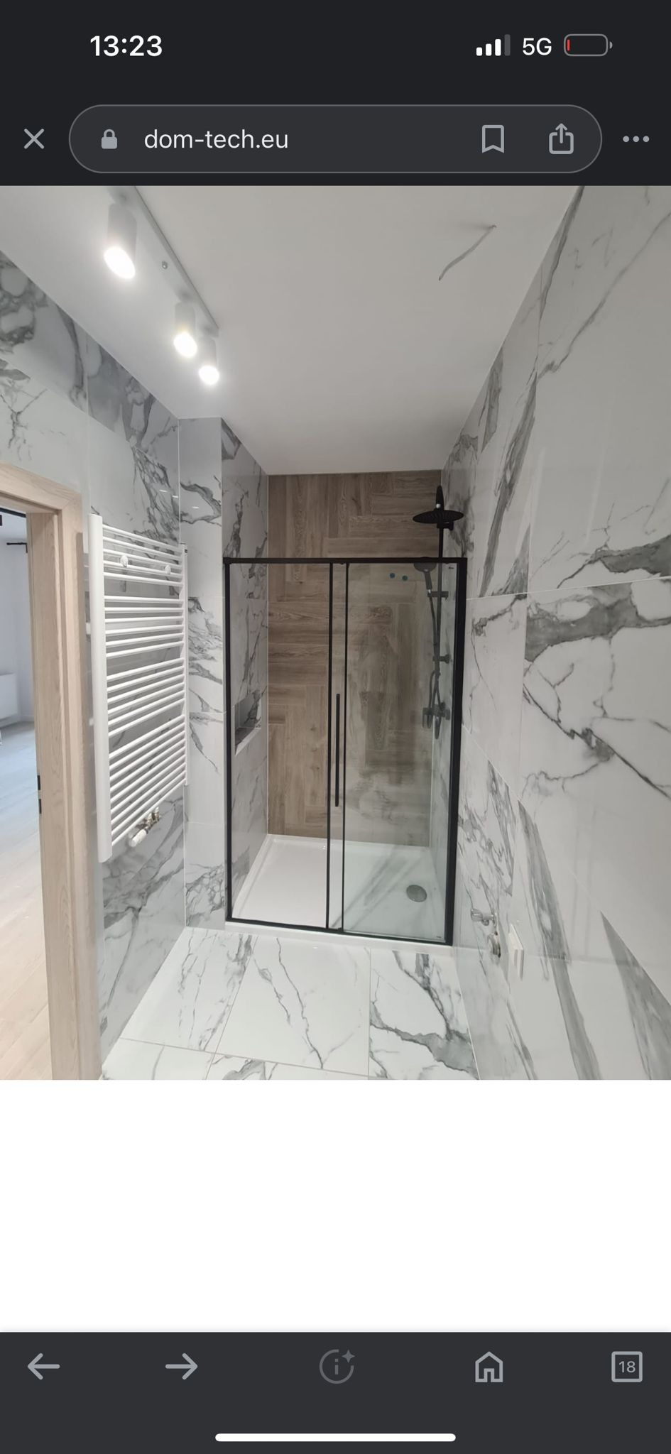 Nowoczesna łazienka z kabiną prysznicową typu walk-in, wykończona płytkami imitującymi marmur i drewno. Widoczny grzejnik drabinkowy.