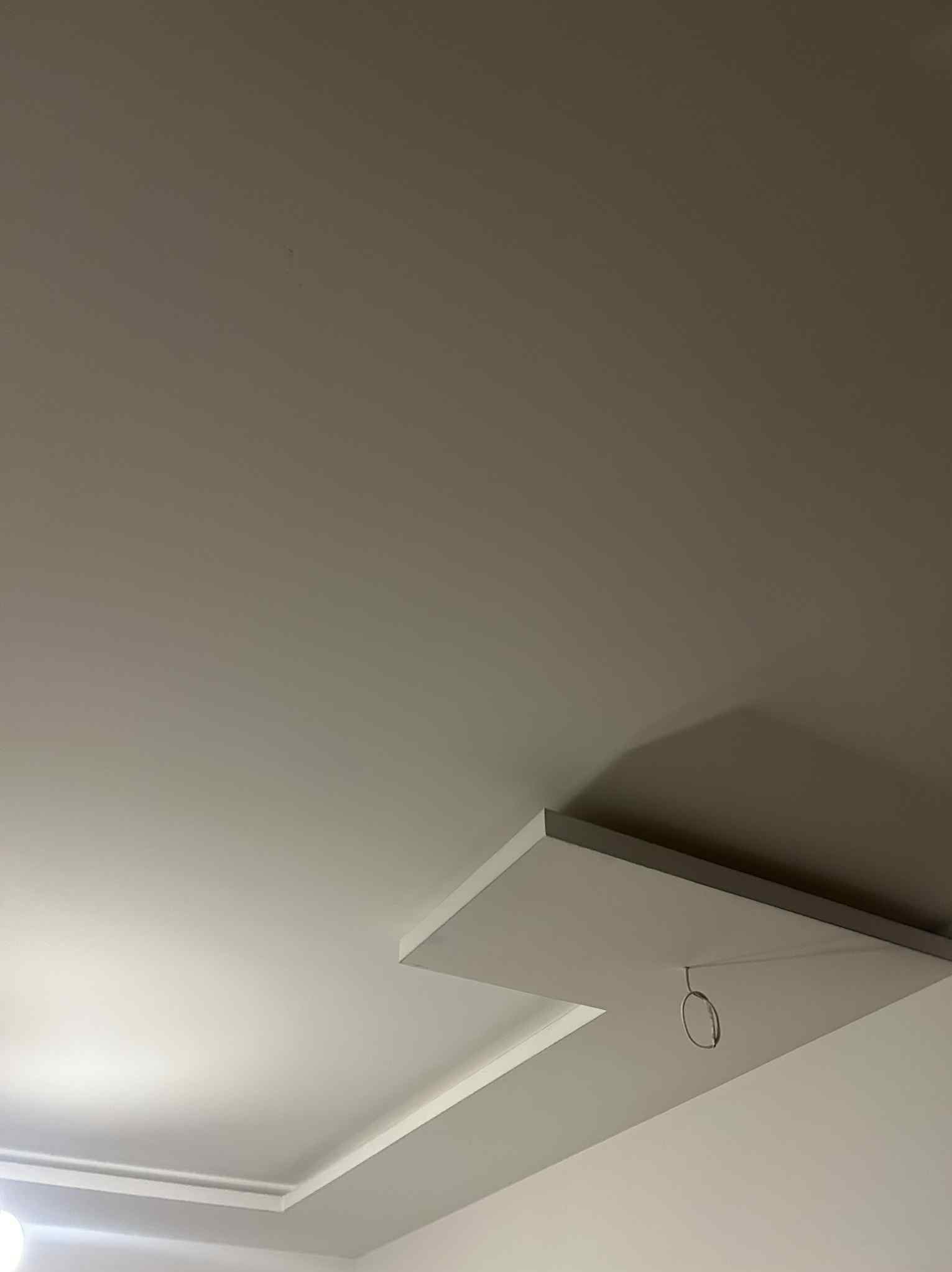 Nowoczesny sufit podwieszany z oświetleniem punktowym w neutralnej kolorystyce, widok od dołu, z delikatnym cieniowaniem i minimalistycznym designem.