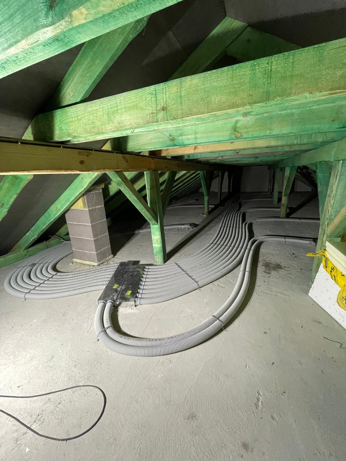 Instalacja rekuperacji z rurami w zielonej więźbie dachowej na poddaszu w Hańsku Pierwszym. Widoczne elementy montażowe i izolacja komina.