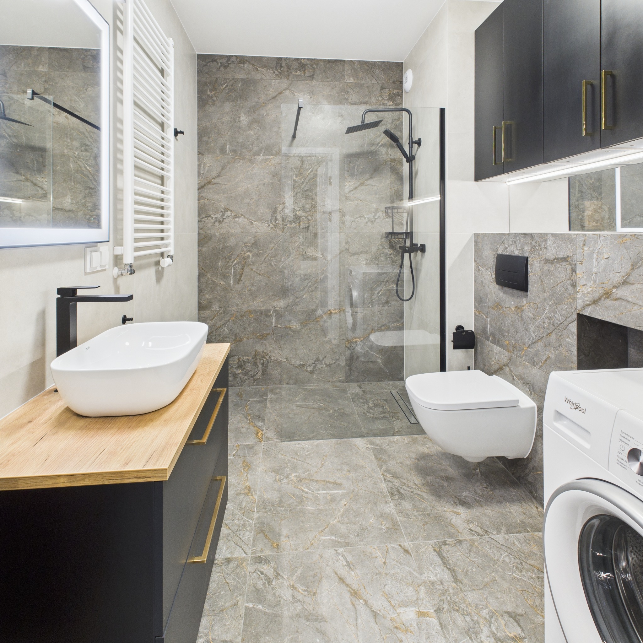Elegancka łazienka z kabiną prysznicową typu walk-in, umywalką nablatową na drewnianym blacie i szarą marmurową okładziną. Nowoczesny design wnętrza.