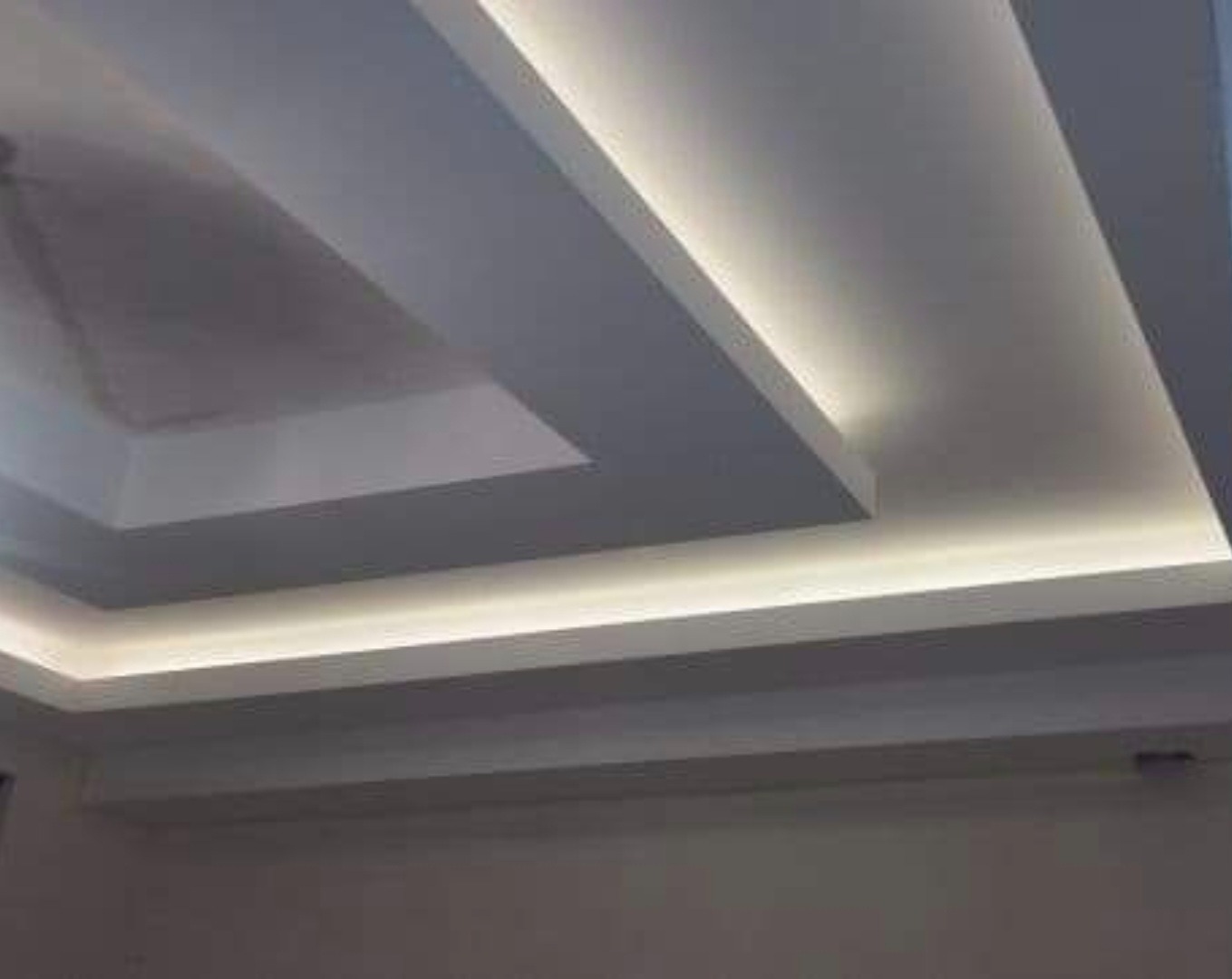 Nowoczesny sufit podwieszany z oświetleniem LED, białe wykończenie, widok z dołu, minimalistyczny design, równomierne światło.