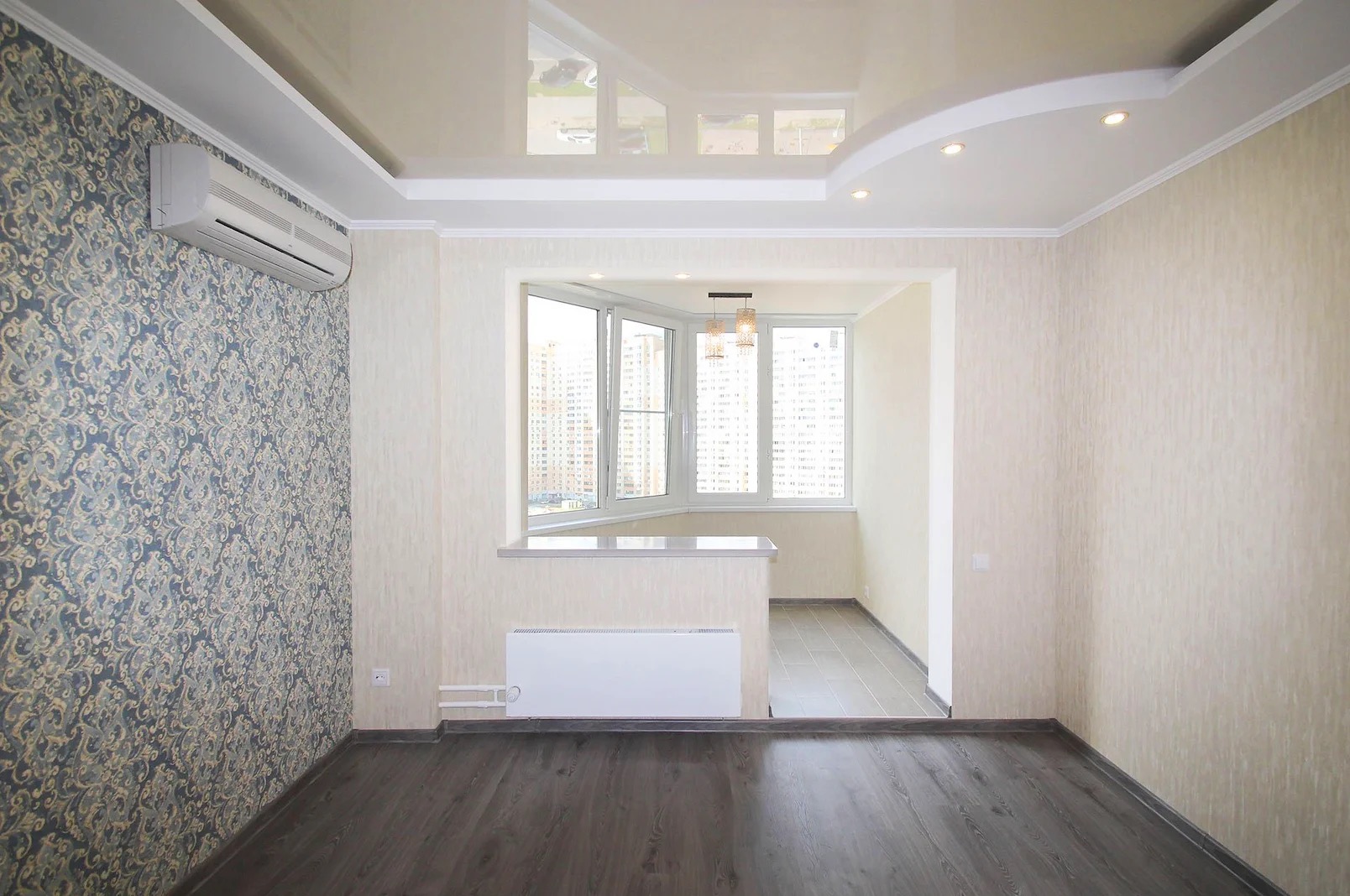 Wykończony balkon z klimatyzacją, wzorzystą tapetą i drewnianą podłogą. Widok na oszklony balkon z oknami i lampą. Sufit podwieszany z oświetleniem punktowym.