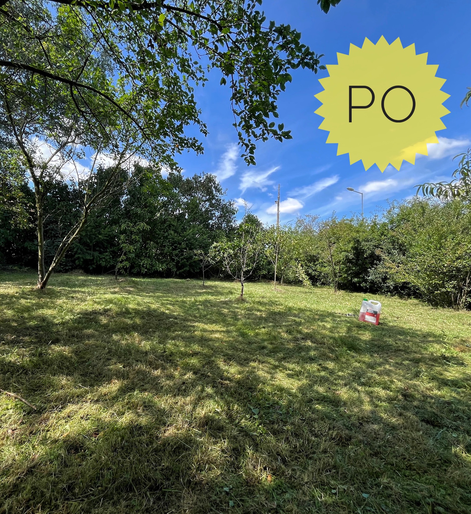 Widok trawnika po koszeniu, z widocznym pojemnikiem na paliwo. Na niebie żółty znak 'PO' sugerujący stan po wykonaniu usługi koszenia.