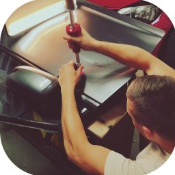 FENIX CENTRUM - Blacharz samochodowy usuwa wgniecenie na karoserii auta przy użyciu specjalistycznego narzędzia. Widok z góry na proces naprawy.