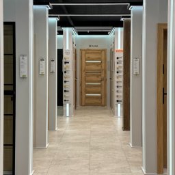WEPA KAWA SPÓŁKA KOMANDYTOWA - Salon z ekspozycją drzwi wewnętrznych różnych modeli, oświetlony ledami, z drewnianą okleiną i przeszkleniami, widok z perspektywy korytarza.