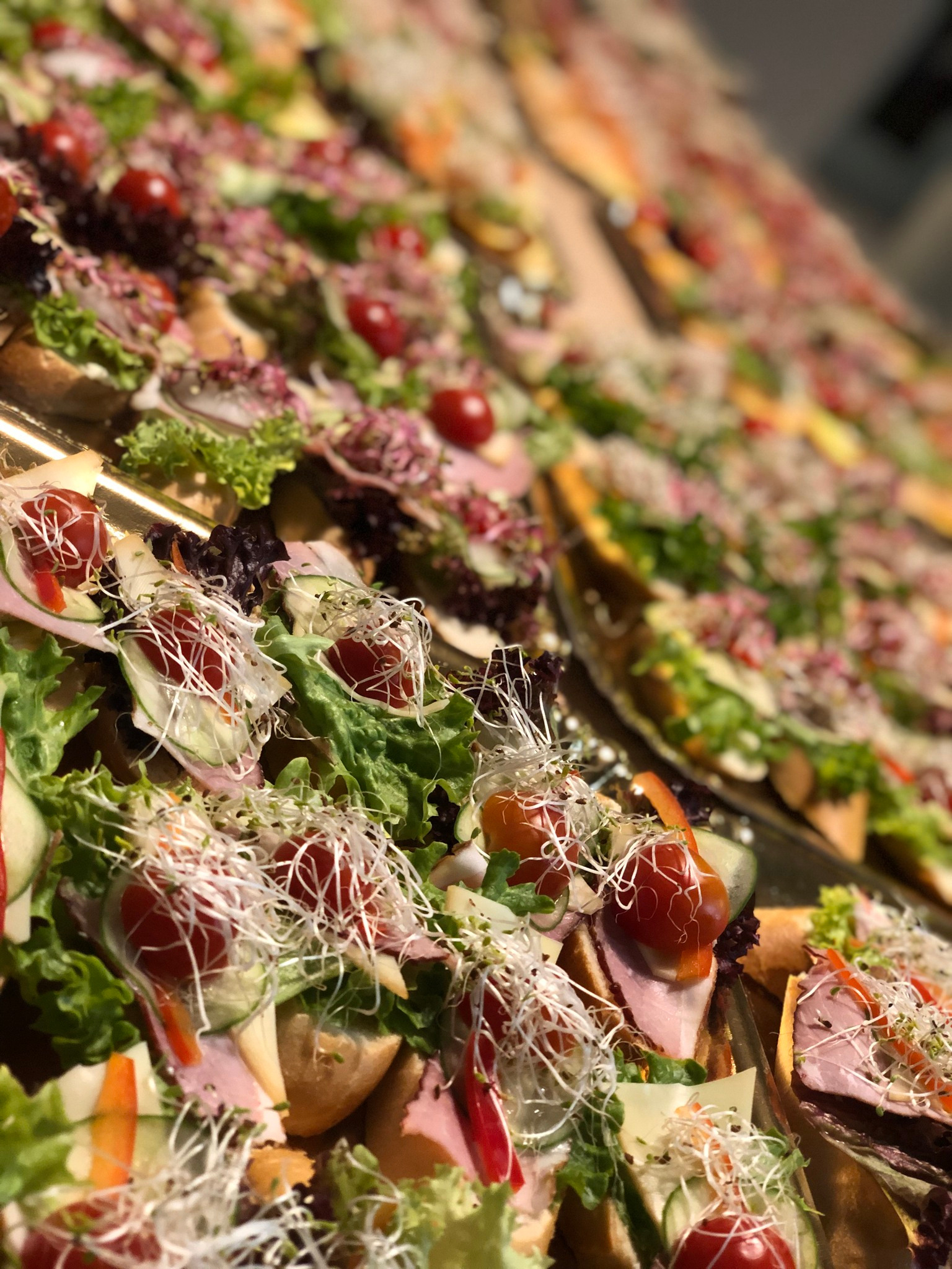 Apetyczne kanapeczki na złotej tacy, dekorowane świeżymi warzywami i kiełkami, gotowe do serwowania na imprezie. Ujęcie z bliska, podkreślające detale.