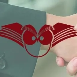 Dłoń podaje wizytówkę z logo sowy i otwartych ksiąg na tle ciemnego garnituru. Symbol wiedzy i profesjonalizmu w finansach i księgowości.