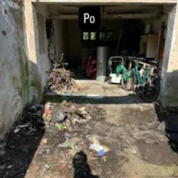 Garaż po opróżnianiu: widoczne rowery, sprzęty, posprzątana podłoga i ściany. Na pierwszym planie cień fotografa. Zdjęcie z napisem 'Po'.