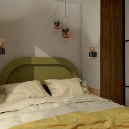 PORADKO DESIGN - Nowoczesna sypialnia z zielonym zagłówkiem, drewnianymi szafami i wiszącymi roślinami. Żółty pled dodaje ciepła wnętrzu. Lampki nocne oświetlają przestrzeń.