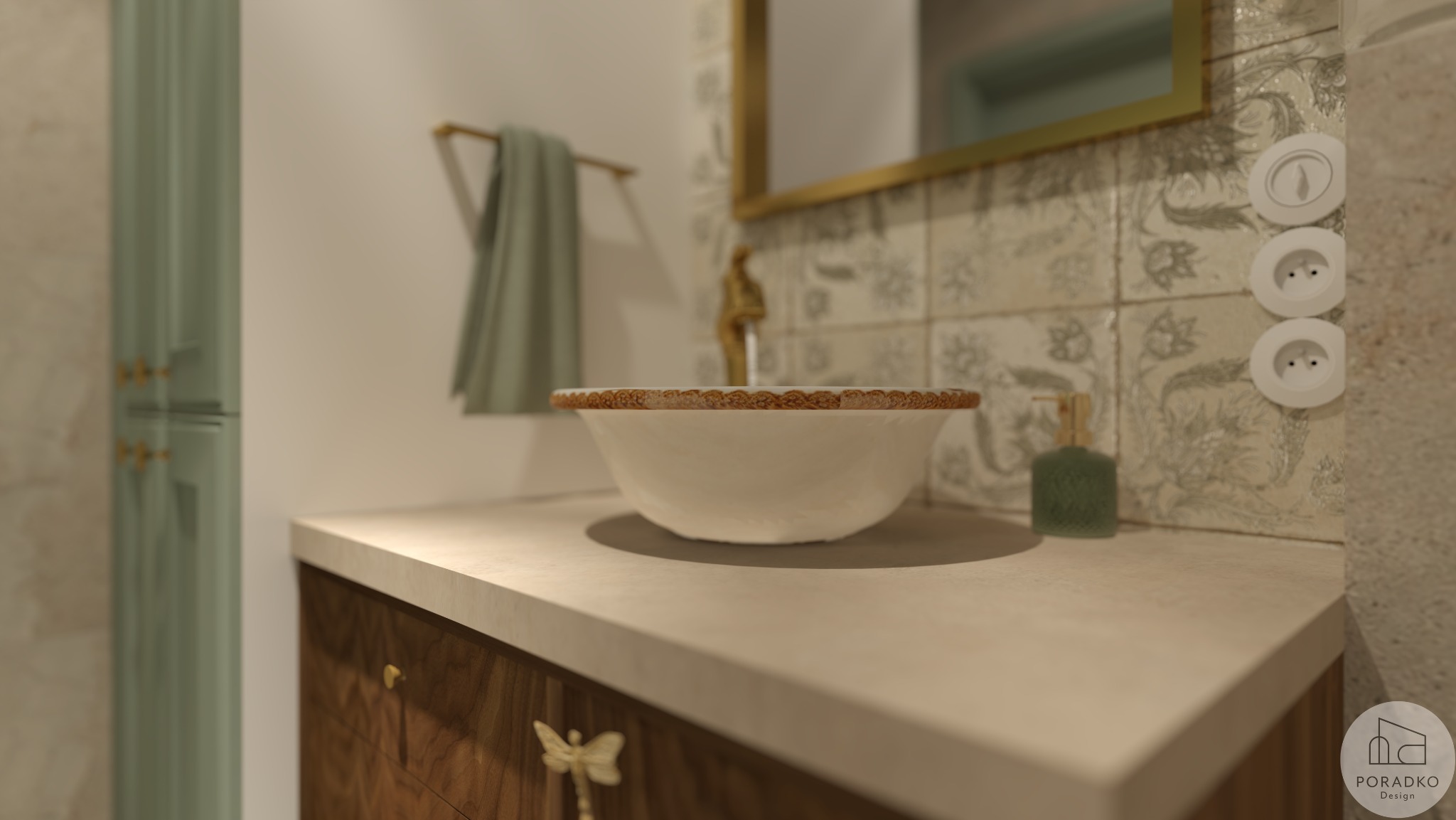 Umywalka nablatowa w łazience z dekoracyjnymi płytkami i złotymi akcentami. Widoczny fragment szafki z ozdobnymi uchwytami i dozownik na mydło.