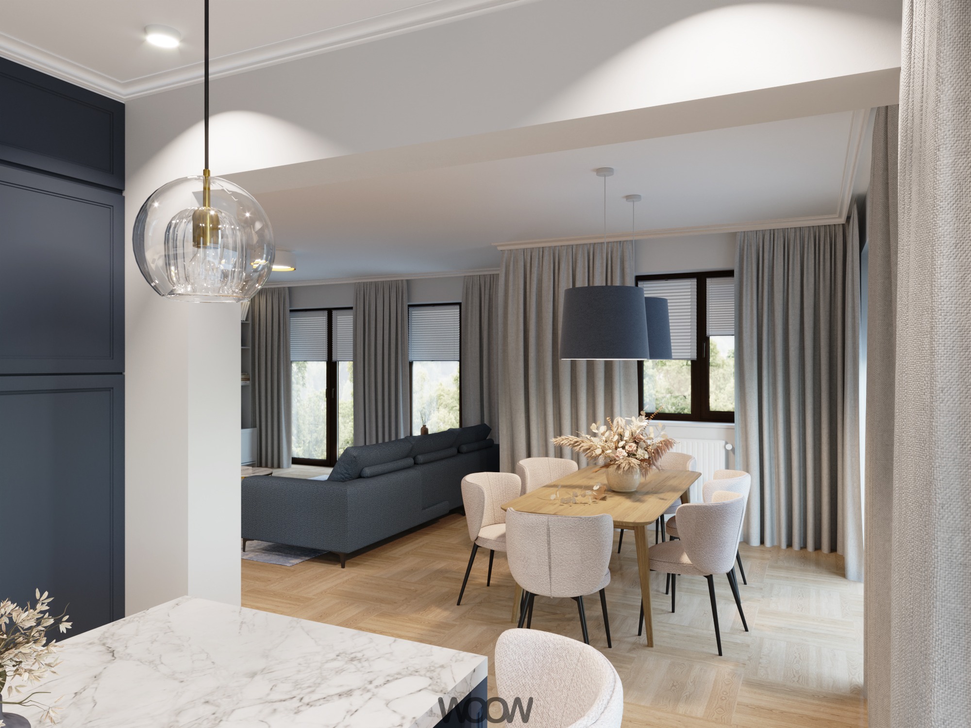 Jasna jadalnia z drewnianym stołem, krzesłami w odcieniach beżu i szarą sofą w tle. Dekoracyjna lampa wisząca nad stołem. Parkiet w jodełkę.