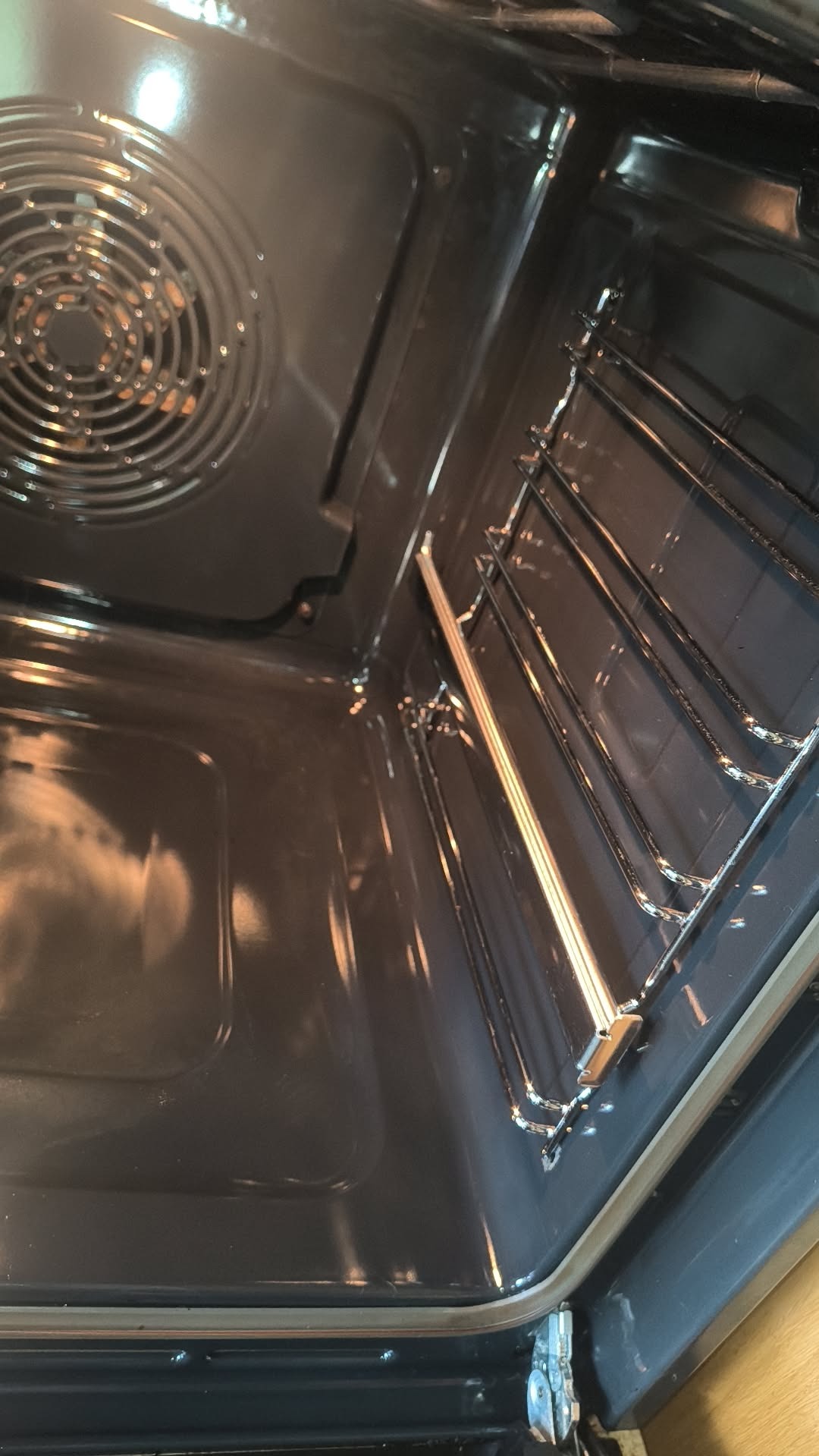 Wnętrze czystego piekarnika po sprzątaniu. Widoczne metalowe prowadnice i grzałka. Brak zabrudzeń i przypaleń. Perspektywa z góry ukazuje detale.