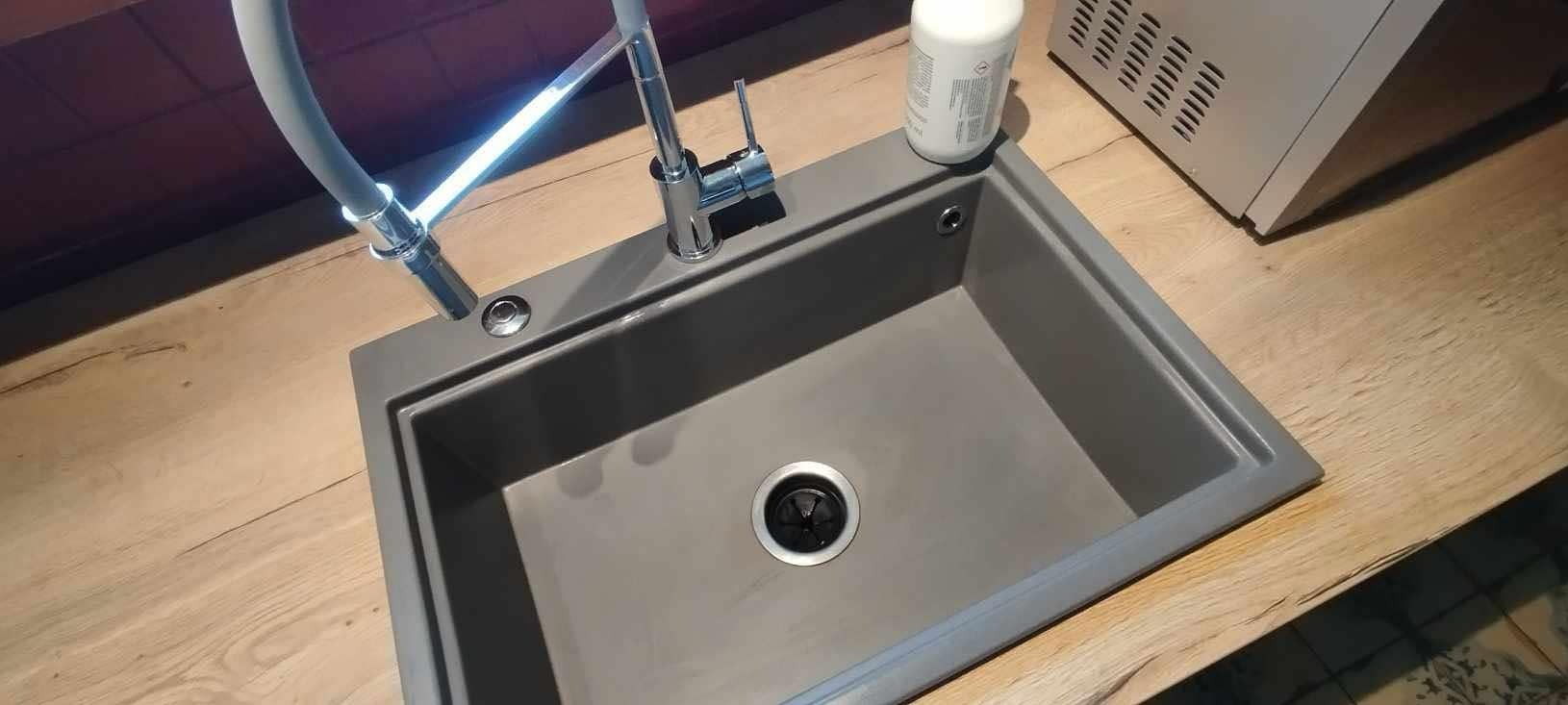 Szary, prostokątny zlew granitowy z baterią i dozownikiem w Olsztynie. Na blacie butelka detergentu. Czysty, gotowy do użytku.