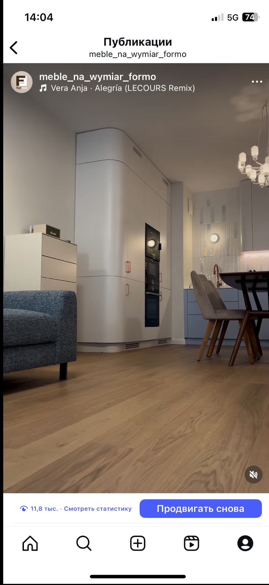 Nowoczesna zabudowa kuchenna na wymiar z zaokrąglonym narożnikiem, piekarnikiem i mikrofalówką, widok z perspektywy podłogi z drewna. Jasne wnętrze mieszkania.